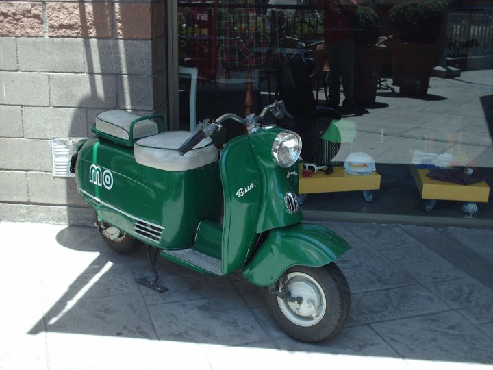 Marque de scooter Fuji Rabbit de couleur verte garé devant un magasin