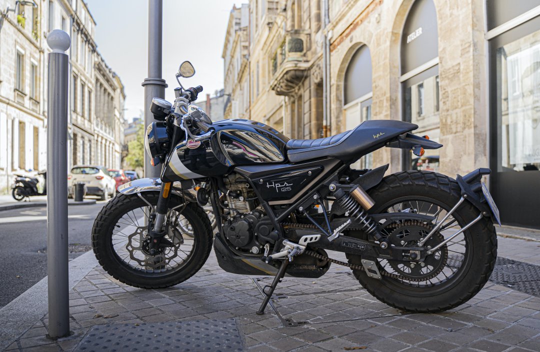 Moto 125 cm3 de couleur noire garée dans une rue ensoleillée