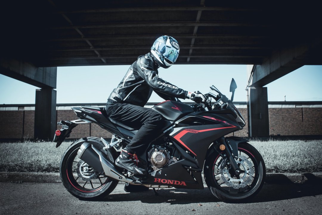Homme se tenant sur une moto japonaise noire et rouge