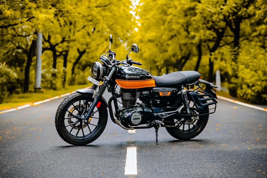 Moto roadster orange et noire garée sur une route de forêt - moto femme