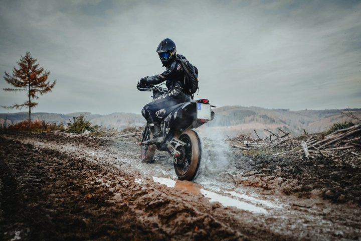 Homme pilotant une moto supermotard sur un chemin boueux