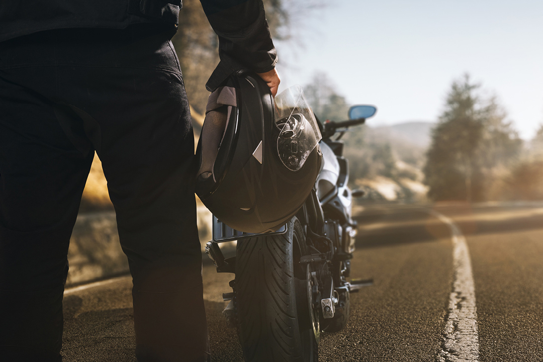 motociclista pé na estrada ao lado de sua moto