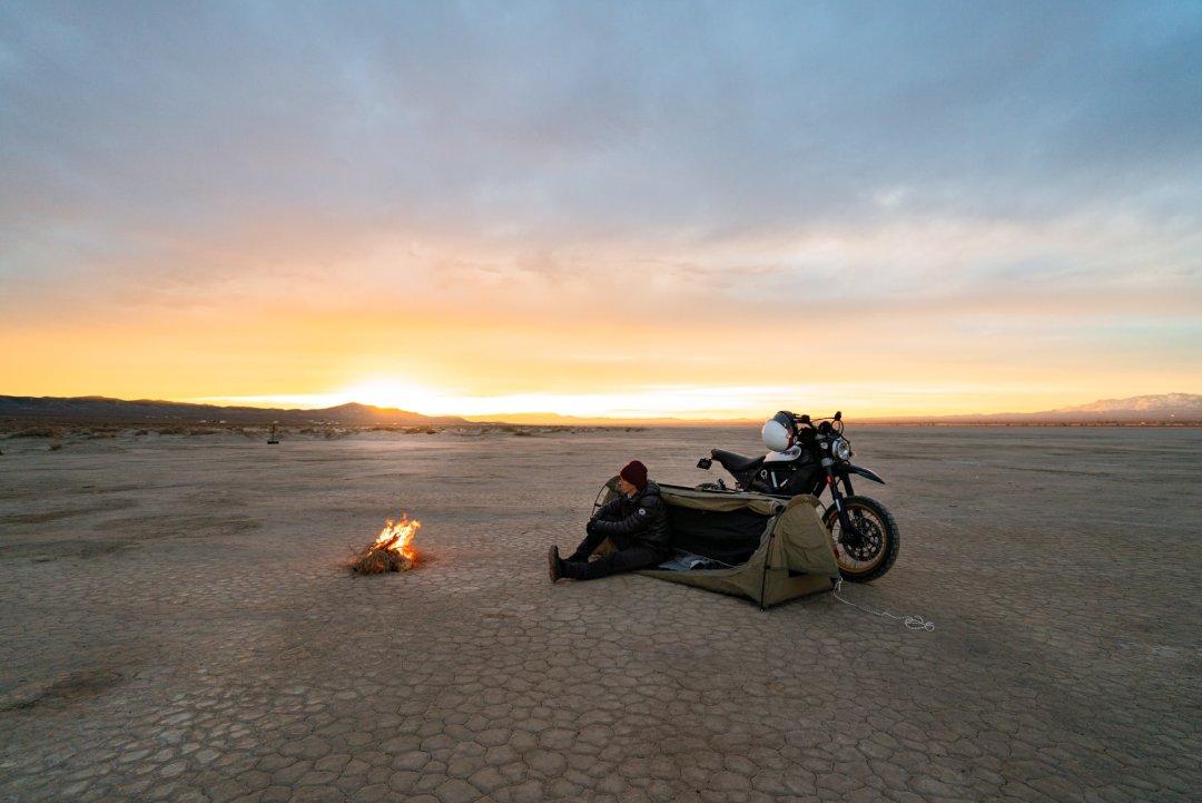 Homme qui bivouac dans le désert durant un moto trip