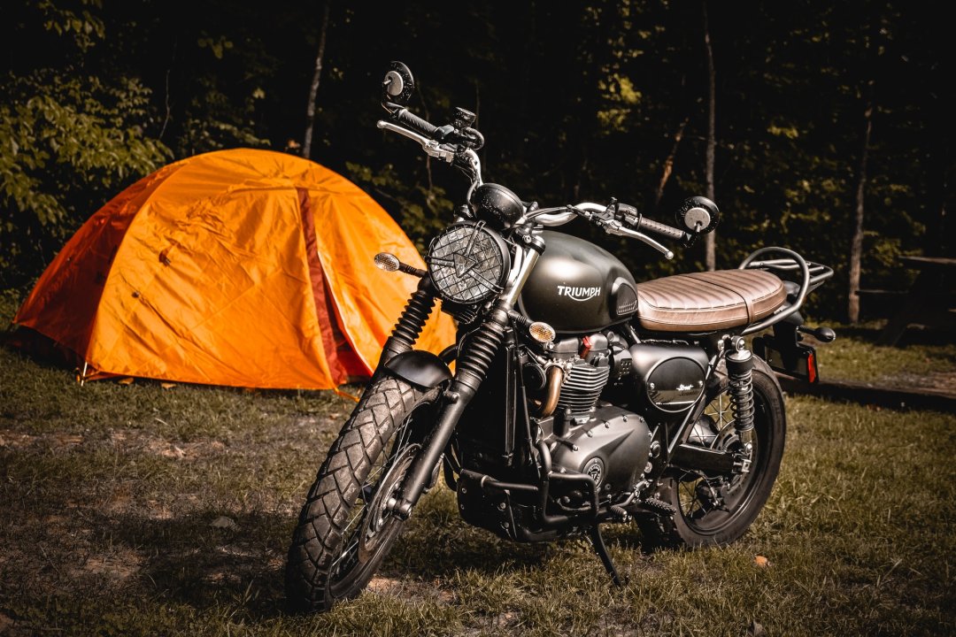 Moto garée dans un camping à côté d’une tente - roadtrip moto