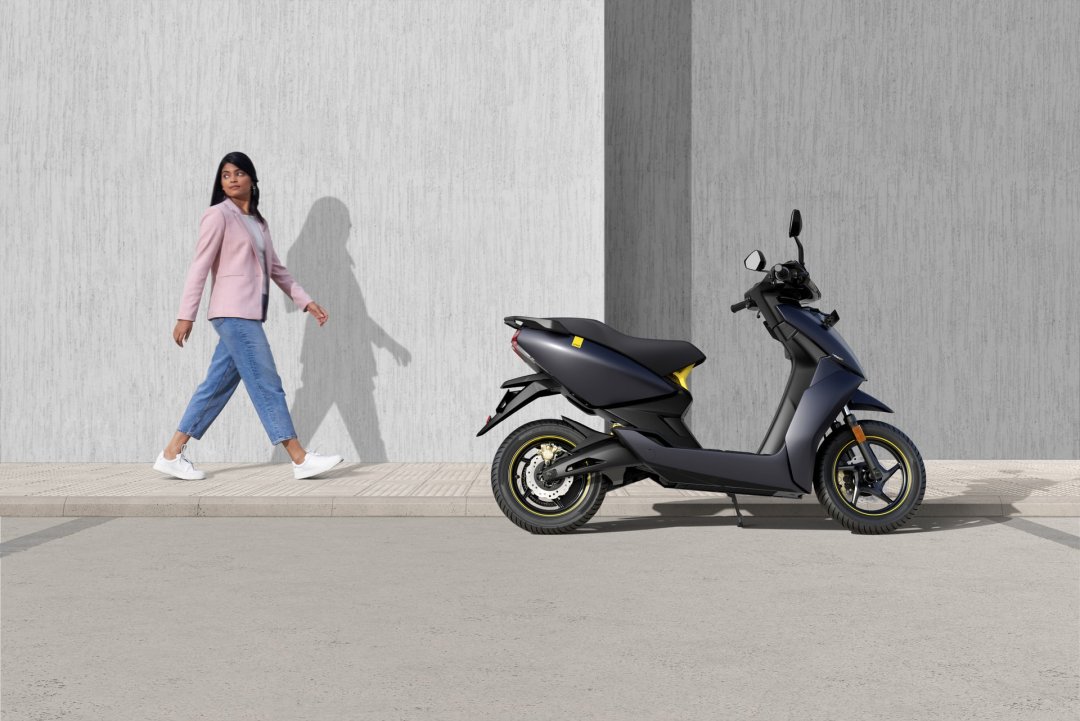 Femme passant près d’un scooter électrique de couleur noire garé dans la rue