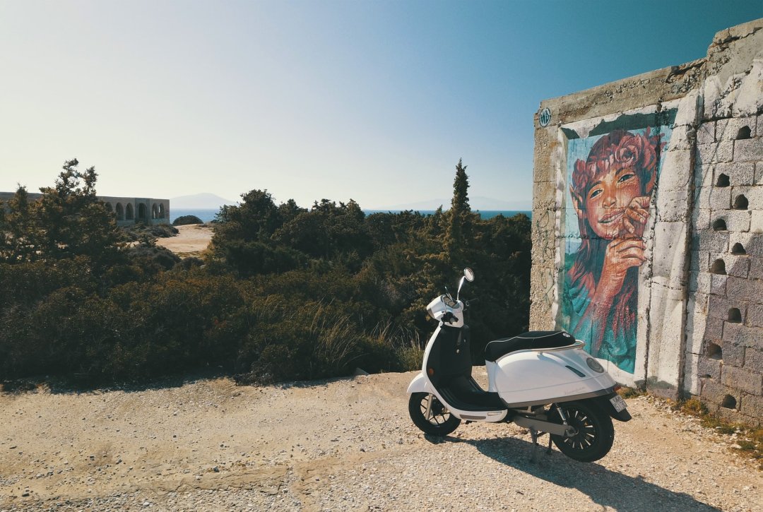 Scooter électrique de couleur blanche garé face à un paysage côtier